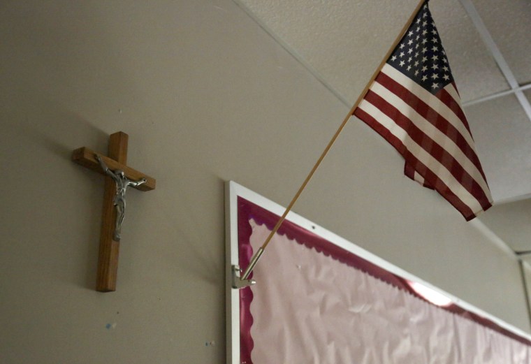 Image: A cross hangs on the wall next to a U.S. flag in an empty classroom at Quigley Catholic High School in Baden, Pa.