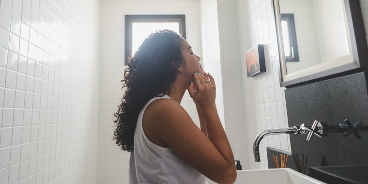 Teenager looking at her face on the mirror in the bathroom