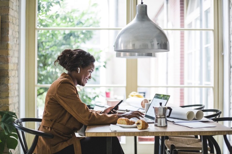 Smiling female architect using phone while sitting at home office