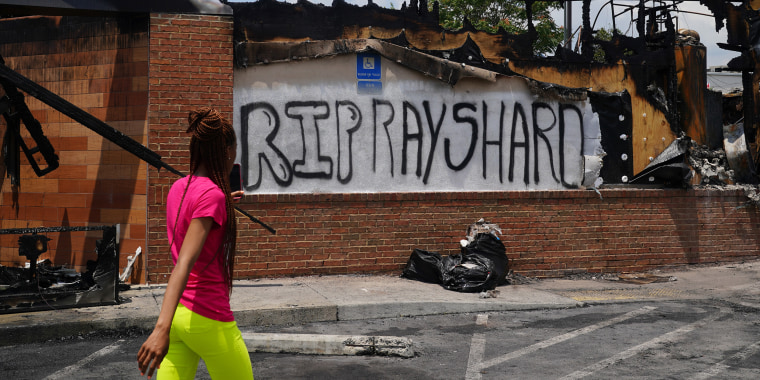 A woman uses her cell phone to document the damage to a burned Wendys restaurant following the police shooting death of Rayshard Brooks in the restaurant parking lot June 14, 2020, in Atlanta.