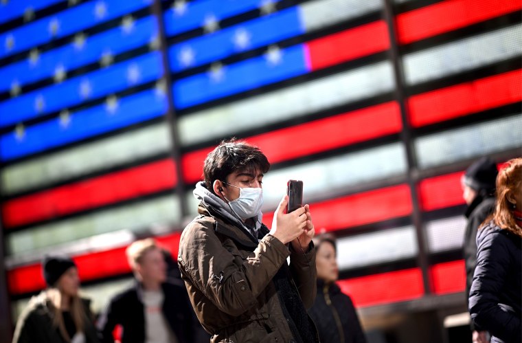 Image: A man uses his cell phone in New York's Times Square on March 5, 2020.