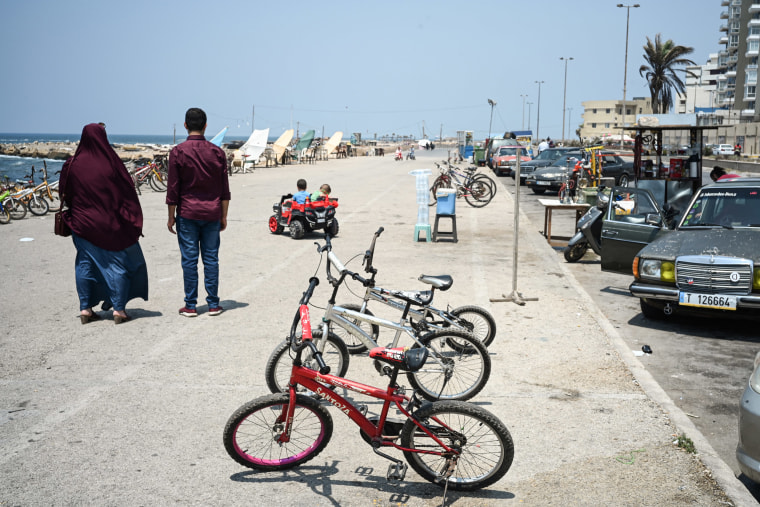 Image: A couple watch their children play on the corniche at Tripoli's sister city of al-Mina
