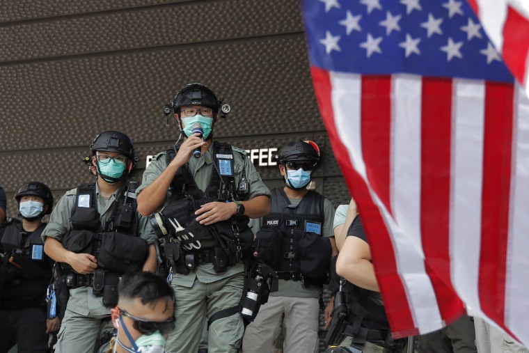 Image: Riot police stand guard in front of an American flag near the U.S. Consulate in Hong Kong, on the Fourth of July 2020.