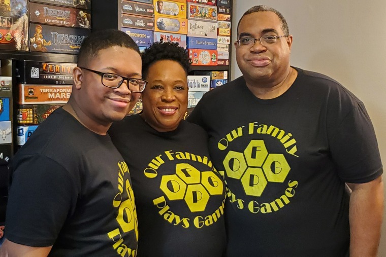 The Fitch family, from left, Grant, Starla and "Mik" smile while wearing shirts bearing the name of their YouTube show, "Our Family Plays Games."
