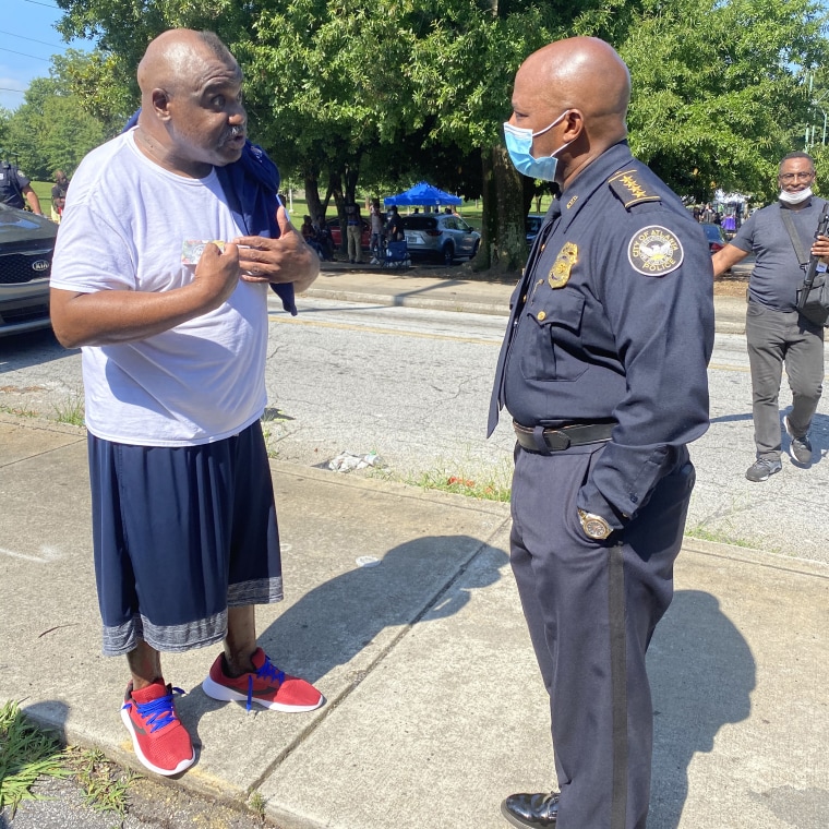 Interim Atlanta Police Chief Rodney Bryant talks to a man as his officers pass out gift cards for groceries to people amid the coronavirus pandemic, courtesy of filmmaker Tyler Perry.