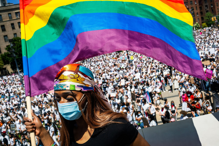 Image: Tiffany Munroe waves a Pride flag during a rally to call attention to violence against transgender people of color in Brooklyn on Sunday, June 14, 2020. (Demetrius Freeman/The New York Times)