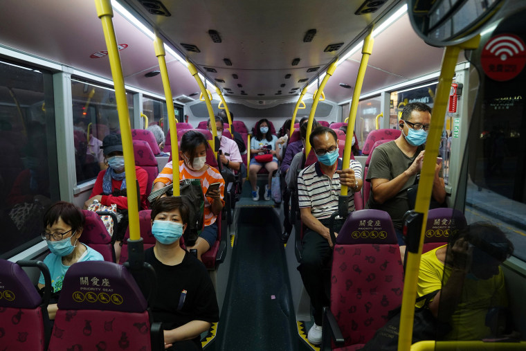 Image: People wearing face masks sit on a bus in Hong Kong