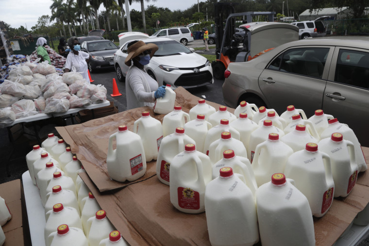 Volunteer Trish Matthews prepares to load a gallon of milk into a vehicle as she works at a food distribution site sponsored by Feeding South Florida in Pembroke Park, Fla., on July 11, 2020.