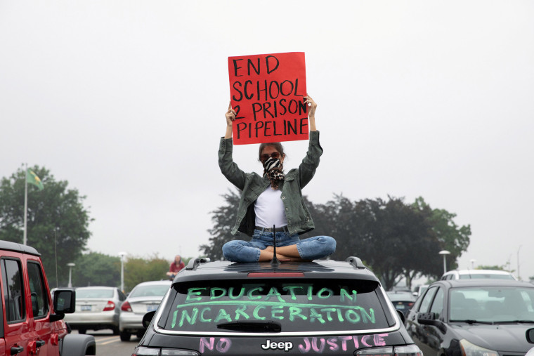 A protester sits on top of a car in support of a Black student at Groves High School in Beverly Hills, Michigan, who was jailed due to a probation violation of not keeping up with her online schoolwork.