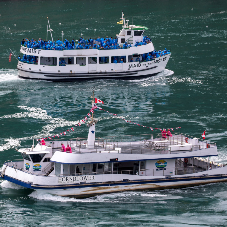 American tourist boat glides past a Canadian vessel limited to just six passengers in Niagara Falls