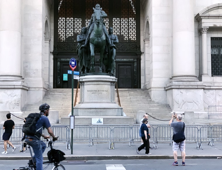 A passerby photographs the statue of Theodore Roosevelt in front of the American Museum of Natural History in New York City on June 22, 2020.