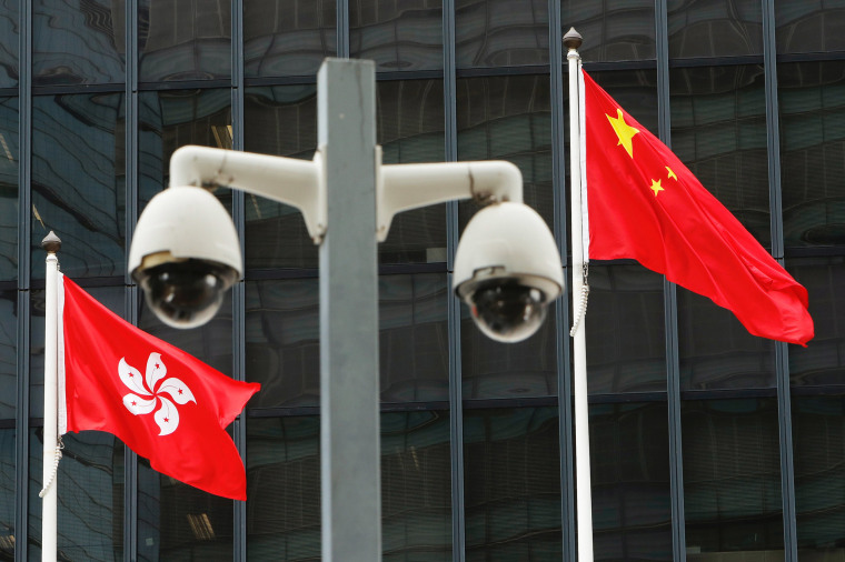 Image: Flags are flown behind a pair of surveillance cameras outside the Central Government Offices in Hong Kong