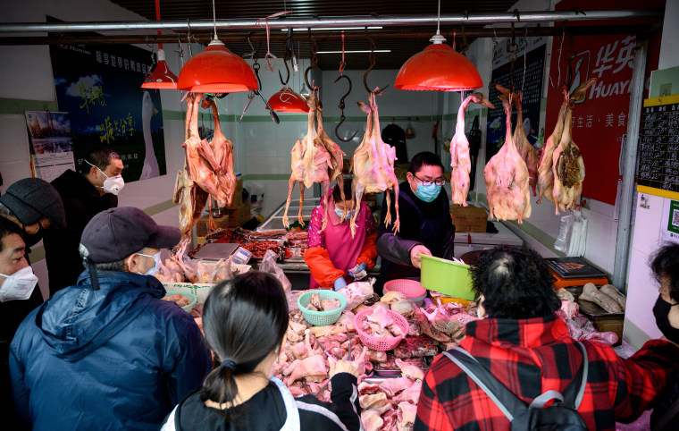 People wearing protective face masks shop at a chicken stall at a wet market in Shanghai on Feb. 13, 2020.