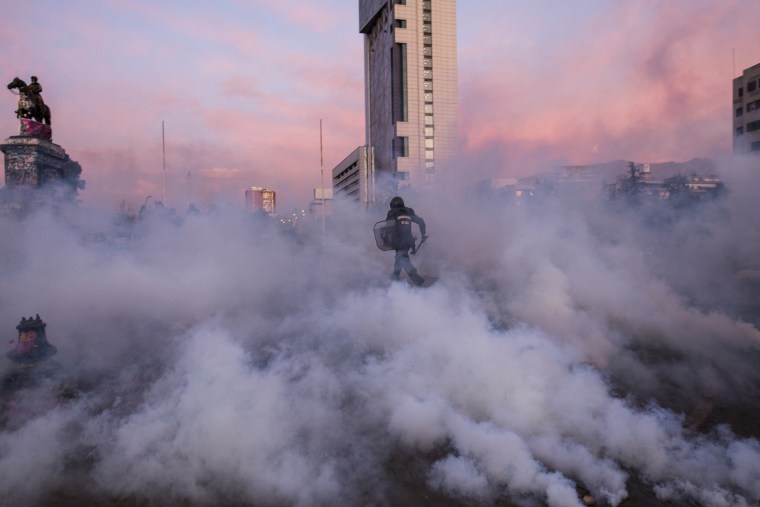 An officer in riot gear runs amidst smoke bombs towards protestors in Plaza Dignidad, formerly Plaza Italia, in Santiago, Chile on Jan. 29th, 2020.