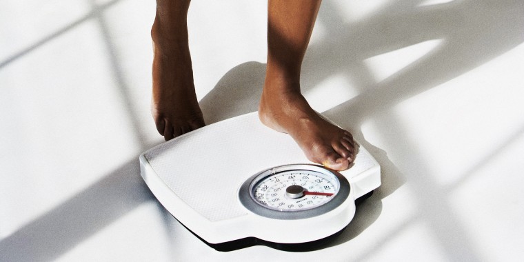 Woman standing on weighing scales, low section
