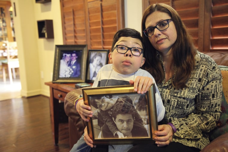 Image: Sergio Cardenas holds a photo of him and his father, detained Citgo executive Gustavo Cardenas, while sitting with his mother, Maria Elena, at their home in Katy, Texas, on Feb. 15, 2019