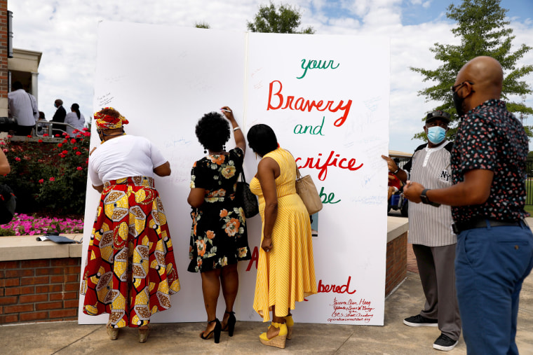 Image: People sign an oversize card for the family of the late U.S. Congressman John Lewis, a pioneer of the civil rights movement and long-time member of the U.S. House of Representatives who died July 17, at Troy University's Trojan Arena in Troy