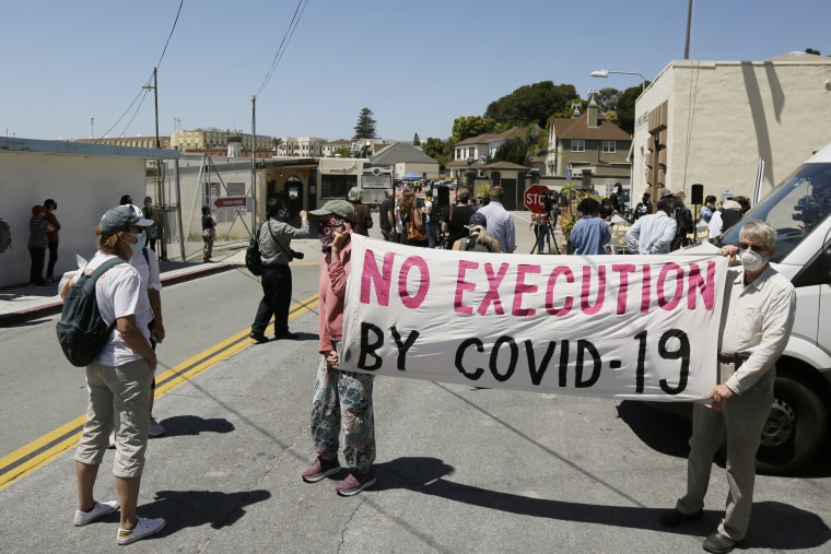 Two men hold up a banner before the start of a news conference outside San Quentin State Prison in San Quentin, Calif., on July 9, 2020.