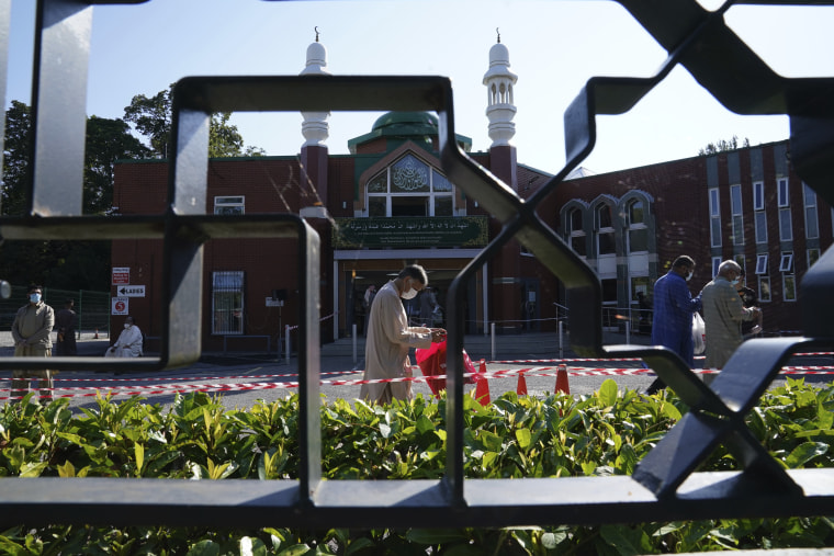 Image: People wearing face masks walk into Manchester Central Mosque in northern England after having their temperatures checked on Friday.