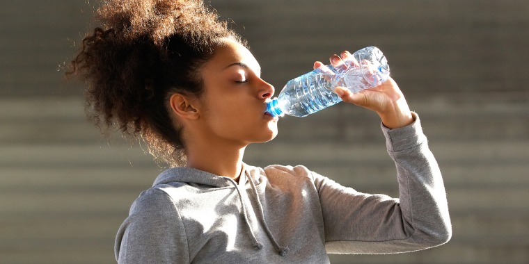 African american sports woman drinking from water bottle