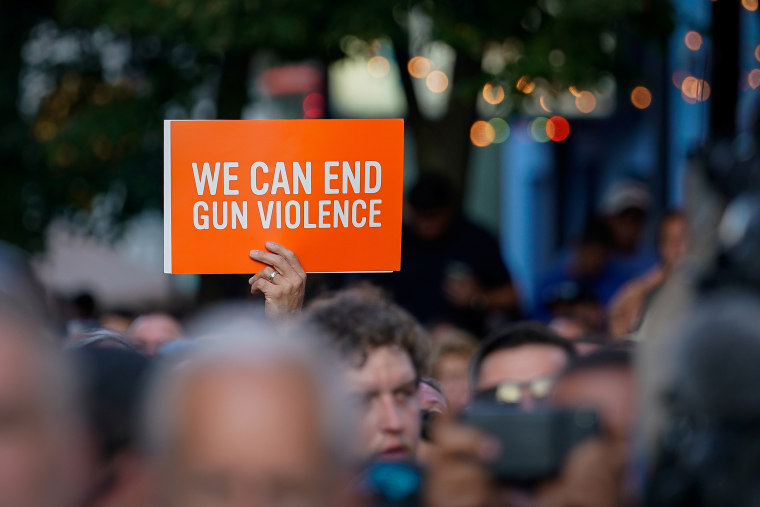 A vigil attendee holds a sign during a vigil at the scene of a mass shooting in Dayton