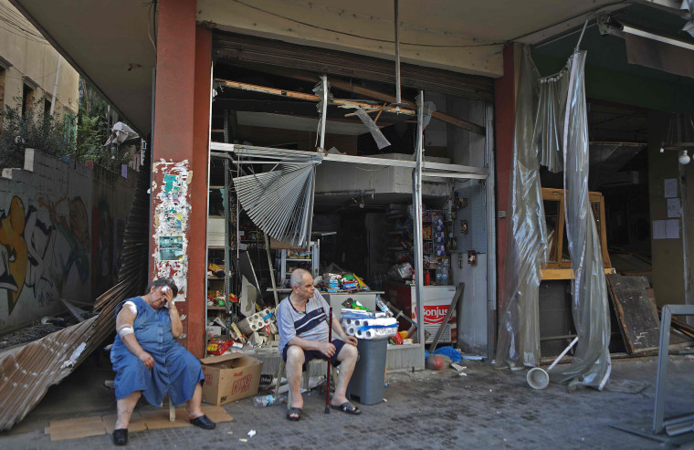 Image: An injured Lebanese woman sits in front of her damaged shop in the Beirut neighborhood of Mar Mikhael on Wednesday.