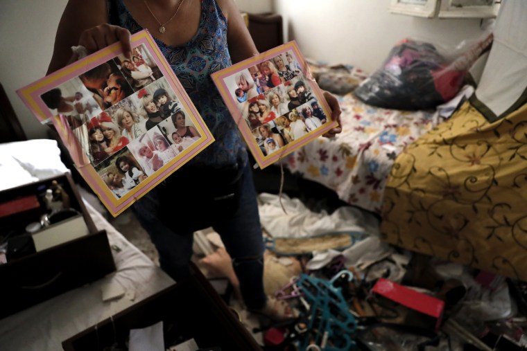 Image: A woman shows pictures of her family in her damaged home