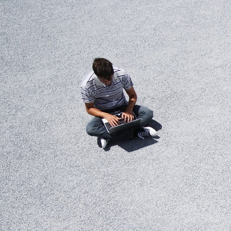 Man sitting on the ground working on his laptop computer