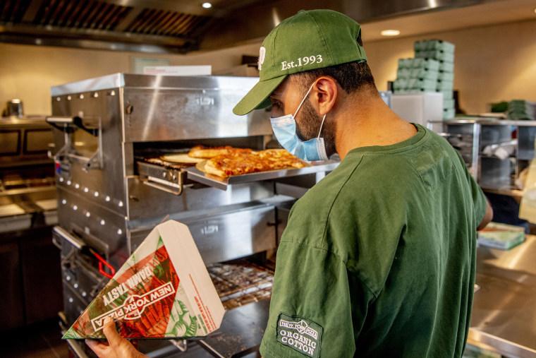 A worker at New York Pizza wearing a mask is seen packaging