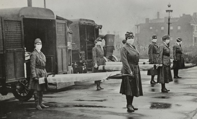 Red Cross Motor Corps. members holding stretchers behind ambulances in St. Louis