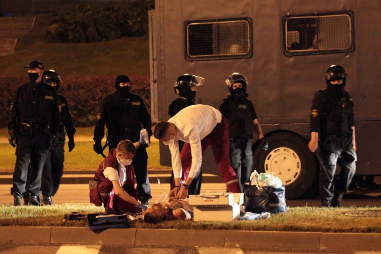 Image: An injured man receives medical help during clashes between opposition supporters and riot police after polls closed in Belarus' presidential election, Minsk