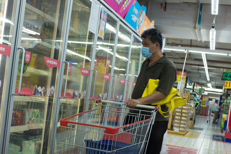Image: A man looks at frozen food products in a supermarket in Beijing