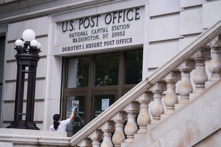 Image: A woman cleans the doors of the National Capital Station U.S. Post Office near Capitol Hill in Washington