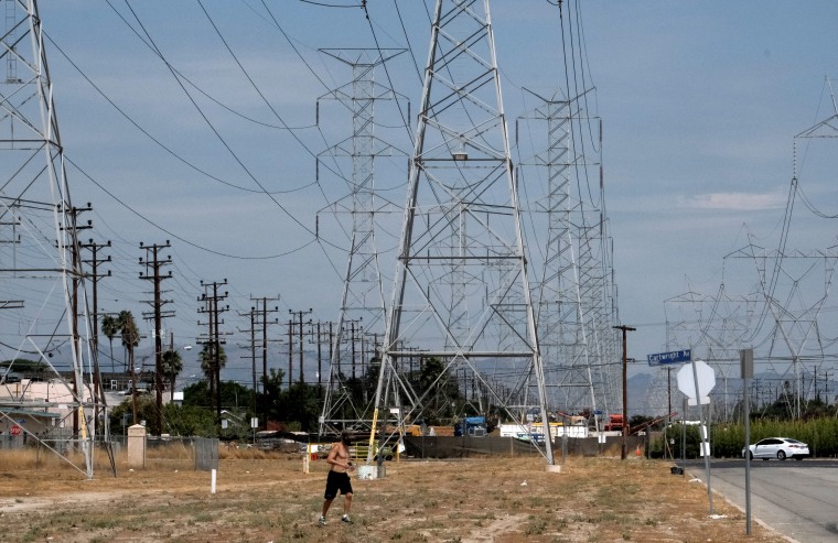 A jogger runs in extreme heat under high tension electrical lines in the North Hollywood section of Los Angeles on Saturday. California has ordered rolling power outages for the first time since 2001 as a statewide heat wave strained its electrical system. 