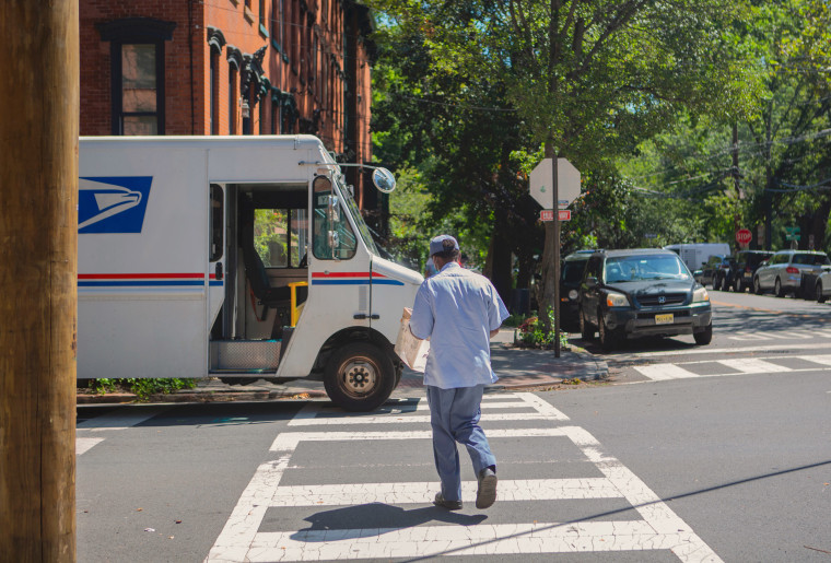 Image: A USPS mail carrier picks up mail from the mailbox on Pavonia Ave. and Coles St. in Jersey City on Aug. 18, 2020.