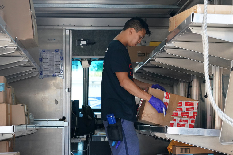 Image: USPS worker sorts packages in his truck in New York City