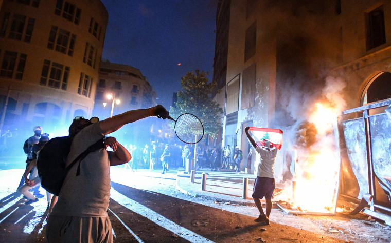 Image: A Lebanese protester uses a tennis racket to throw projectiles during clashes with security forces in downtown Beirut on