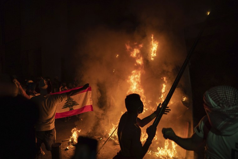 Image: Anti-government protesters burn a barricade next to a wall installed by security forces to block access to the Parliament building, during a demonstration following last week's massive explosion which devastated Beirut, Lebanon,
