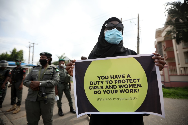 Image: A protester wearing face mask, carries a banner outside the Nigerian Police Headquarters in Abuja, Nigeria, during a demonstration to raise awareness about sexual violence in Nigeria