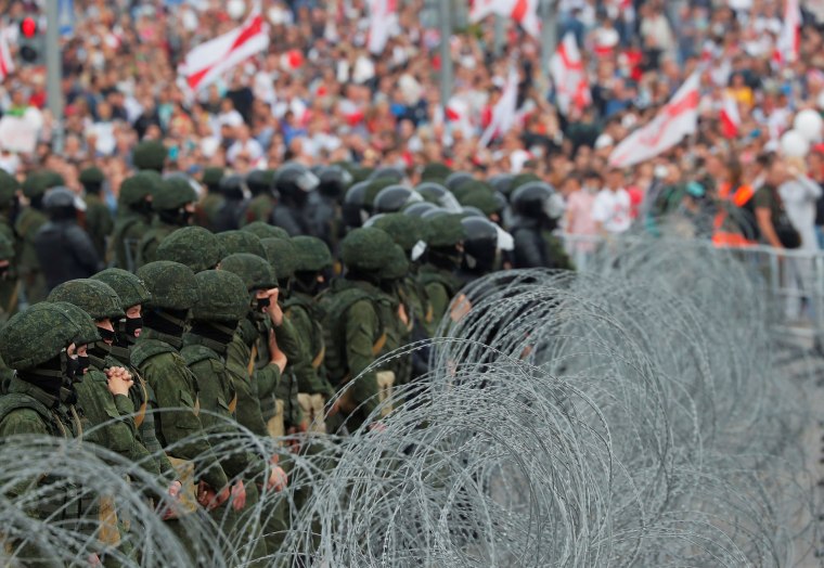 Image: Law enforcement officers stand behind barbed wire during an opposition rally in Minsk on Sunday. 
