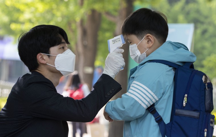Image: A student gets body temperature measured when returning for classes at Seryun Elementary School in Seoul, South Korea