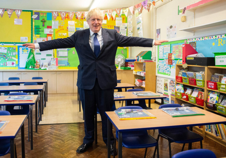 Image: Britain's Prime Minister Boris Johnson poses with his arms out-stretched in a classroom as he visits St Joseph's Catholic Primary School in Upminster, east London