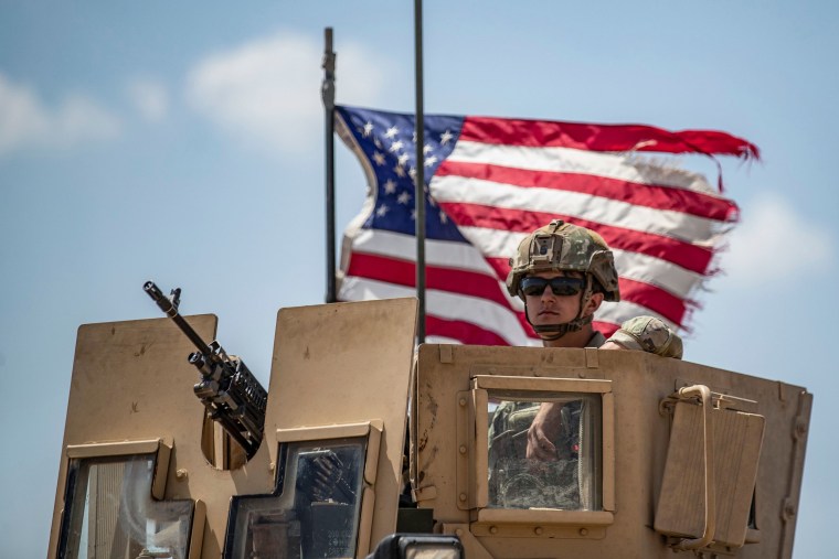 Image: A U.S. soldier sits atop a vehicle in a convoy patrolling an area in the countryside of Tal Tamr town, in Syria's northeastern Hasakeh province near the border with Turkey