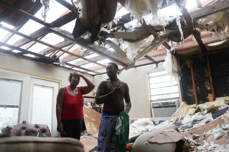 Image: Latasha Myles and Howard Anderson stand in their living room where they were sitting when the roof blew off