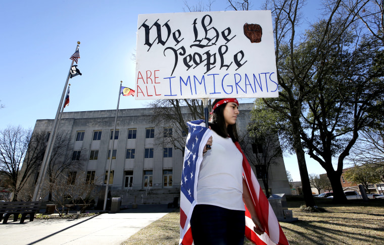 A high school senior holds a sign outside the Grayson County Courthouse during an action called A Day Without Immigrants in Sherman, Texas, on Feb. 16, 2017.