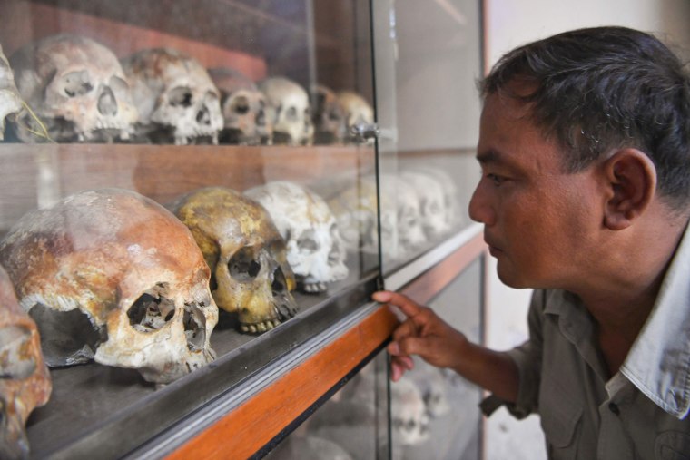 Image: Norng Chan Phal, who survived internment at the Tuol Sleng prison known as S-21 as a child, looks at skulls displayed at the Tuol Sleng genocide museum in Phnom Penh