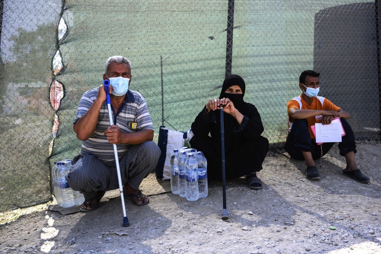 Image: Migrants sit outside the perimeter of the Moria refugee camp on the northeastern Aegean island of Lesbos, Greece