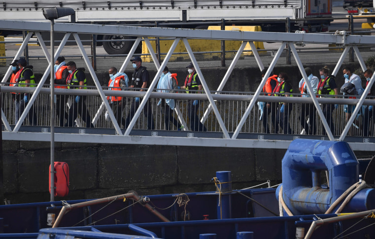 Image: UK Border Force officials escort migrants on the quayside after they were intercepted by Border Force whilst travelling in a RIB from France to Dover, at the Marina in Dover,