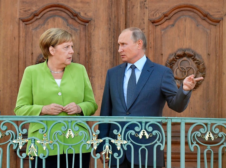 Image: German Chancellor Angela Merkel and Russian President Vladimir Putin chat as they pose for the media at Schloss Meseberg castle in Meseberg, northeastern Germany.