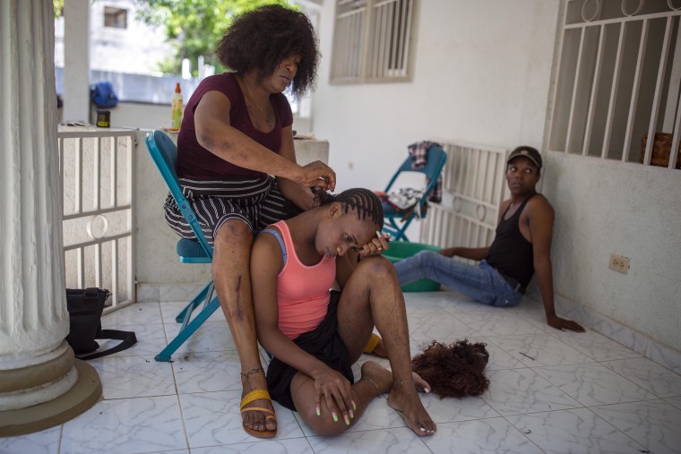 Image: Transgender Laurent Voltus braids the hair of her roommate Vlajimy Cesar as they sit on the porch of the Kay Trans Haiti center where they live, in Port-au-Prince, Haiti